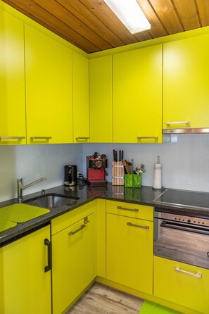 A kitchen with yellow cabinets, a stainless steel sink, and a wooden countertop. - Sportina 12 1. OG Süd Appartement/Fewo, Dusche, WC by Interhome (Riederalp)