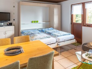 Ein kleines Zimmer mit einem Bett, einem Fernseher, einem Tisch und einem Stuhl.