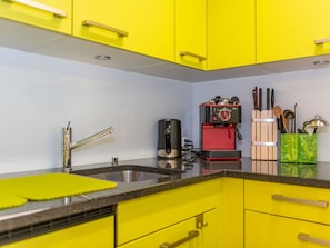 A kitchen with yellow cabinets, a stainless steel sink, and a red coffee maker. - Sportina 12 1. OG Süd Appartement/Fewo, Dusche, WC by Interhome (Riederalp)