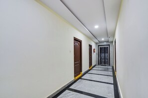 A corridor with doors on one side and a tiled floor. - Super Townhouse Hitech City Madhapur (Hyderabad)