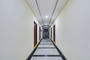 A corridor with doors on both sides, a tiled floor, and a ceiling with recessed lighting. - Super Townhouse Hitech City Madhapur (Hyderabad)