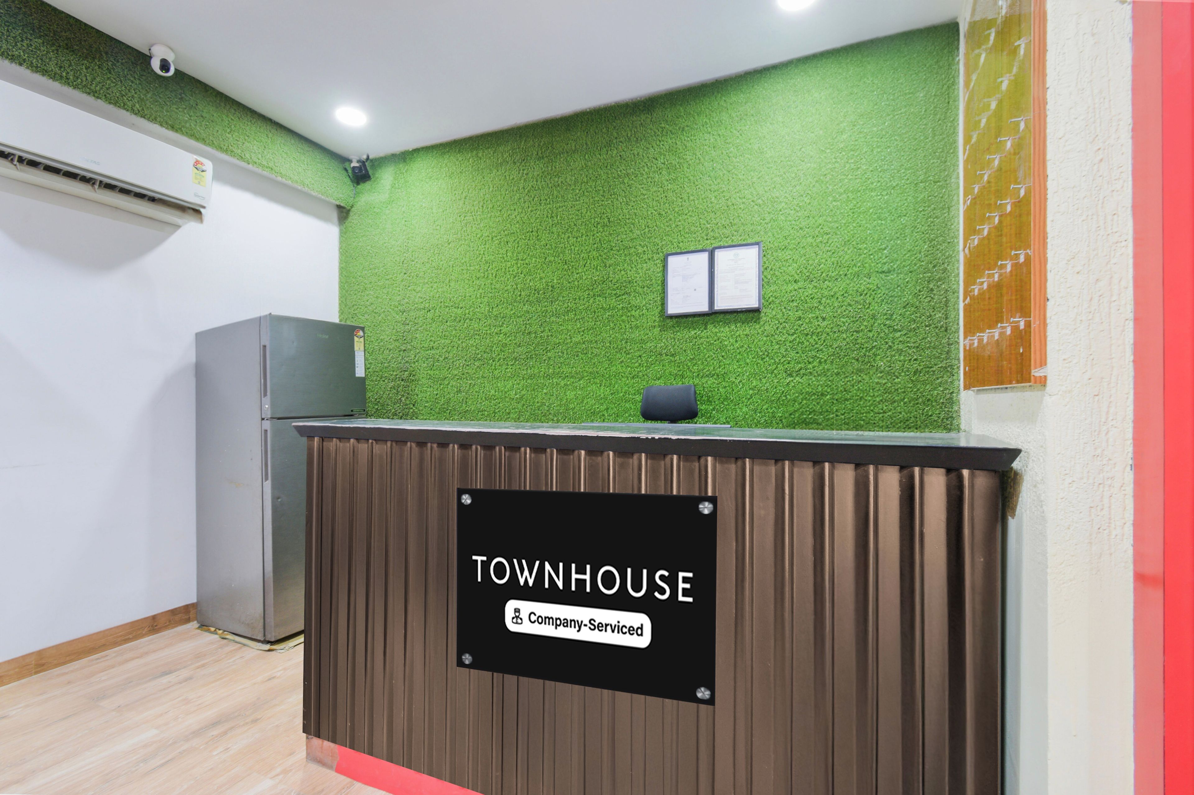 Een receptiebalie met een bord waarop 'TOWNHOUSE & Company Serviced' staat.