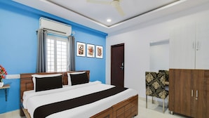 Une chambre à coucher comprenant un lit, une armoire, un ventilateur de plafond, une fenêtre avec des rideaux et des œuvres d’art murales.