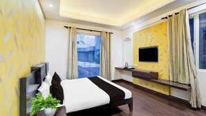Een moderne hotelkamer met een groot bed, een aan de muur bevestigde televisie, een kleine kitchenette en uitzicht op buiten.