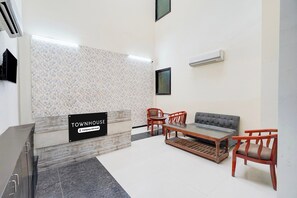 A reception area with a sign indicating it's company-serviced. There are two chairs, a sofa, and a coffee table. - Townhouse Sector 51 Noida (Noida)