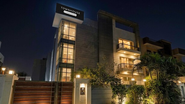 Een modern herenhuis met een opvallende ingang, een balkon en een goed verlichte gevel.