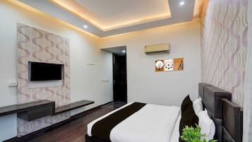 Un dormitorio moderno con una cama, un televisor montado en la pared y un equipo de aire acondicionado.
