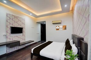 A modern bedroom with a bed, a TV mounted on the wall, and an air conditioning unit. - Townhouse Sector 51 Noida (Noida)