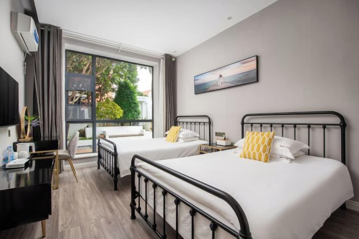 Una habitación de hotel con dos camas, un escritorio y un ventanal grande.