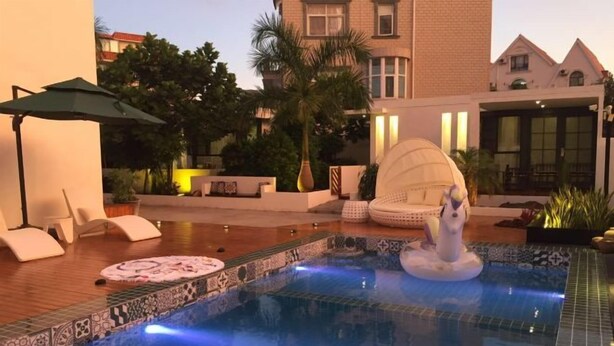Área de piscina com espreguiçadeiras, uma fonte decorativa e um deck revestido de azulejos.