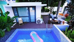 Piscina com escada, rodeada por um terraço com assentos e ventoinha.
