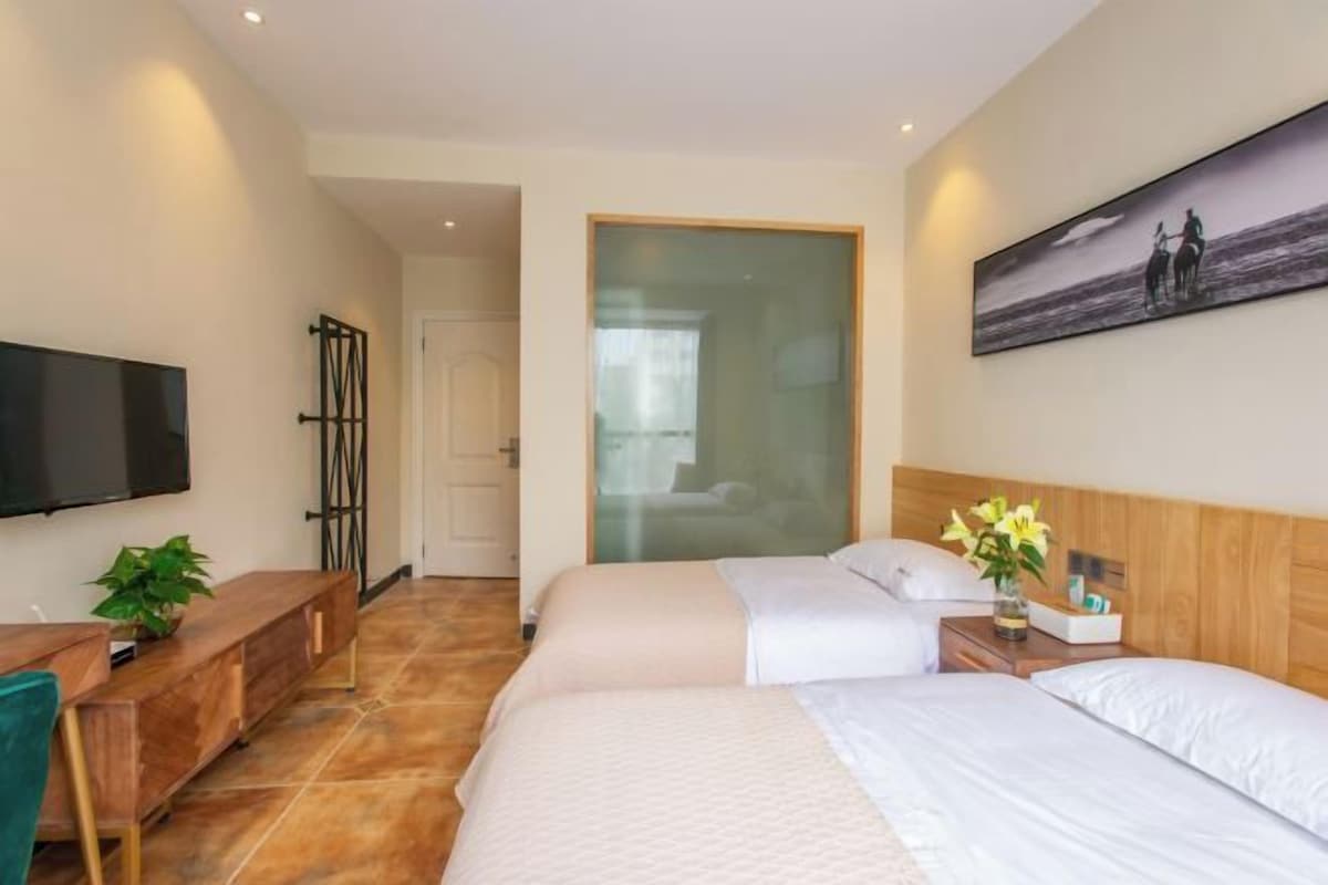 Habitación de hotel con dos camas, un televisor, un escritorio y un cuadro en la pared.