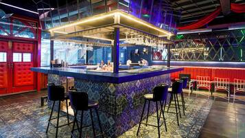 A bar area with a blue counter, stools, and a patterned floor.