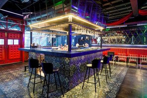 Un espace bar avec un comptoir bleu, des tabourets et un sol à motifs.
