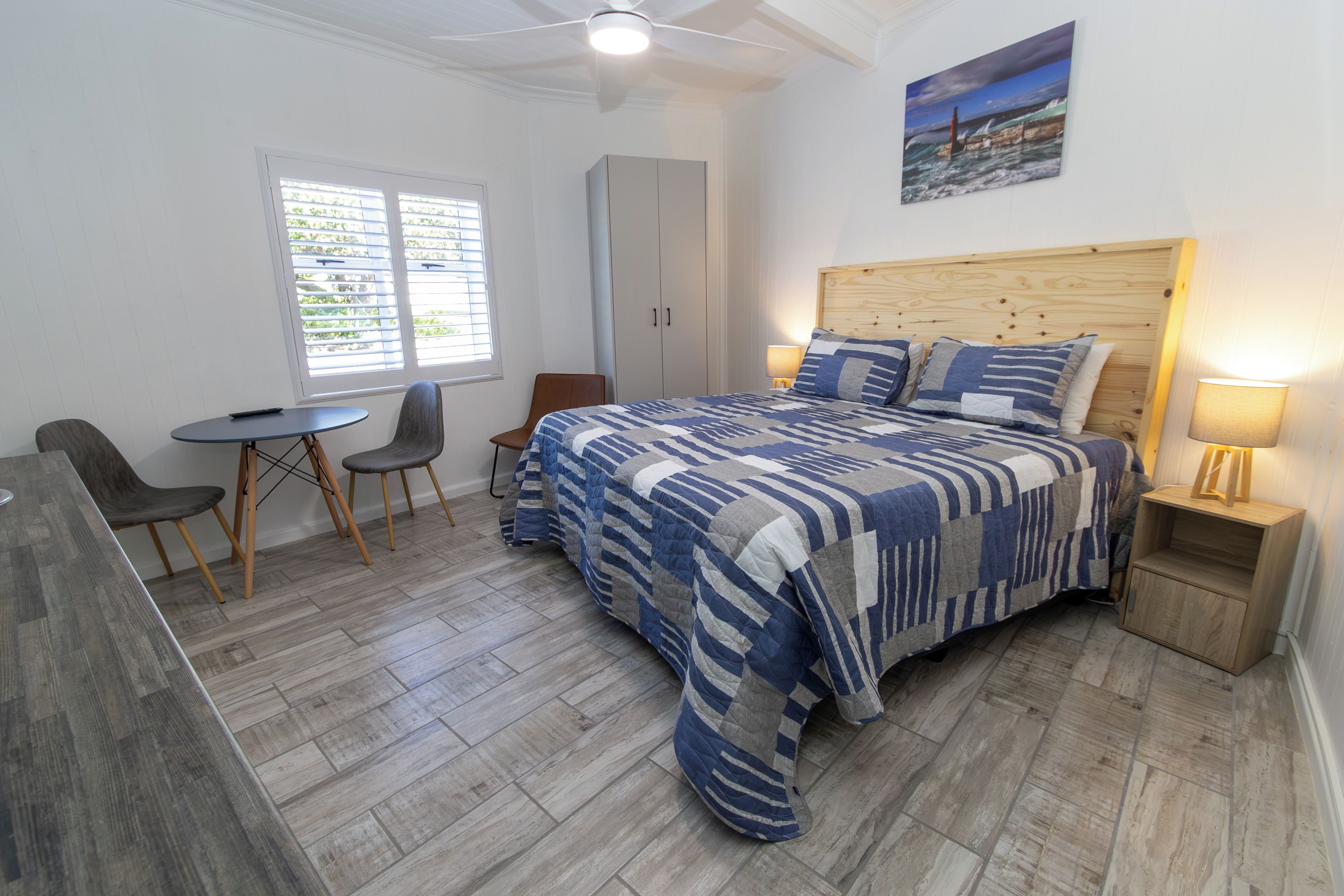 A bedroom with a bed, a desk, a chair, a wardrobe, and a window.
