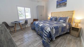 A bedroom with a bed, a desk, a chair, a wardrobe, and a window.