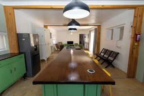 A kitchen with a long wooden countertop, green cabinets, and a black refrigerator.