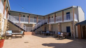 A hotel with a central courtyard, outdoor seating, and a staircase connecting the floors.