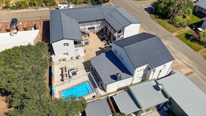 Um edifício com vários andares, piscina, área de estar externa e estacionamento.