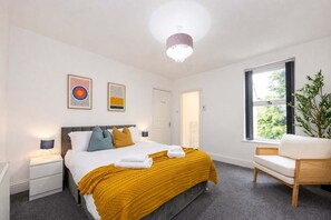 A hotel room with a bed, bedside tables, a window with a view, a chair, and artwork on the wall. - The Hale Loft- Sleeps 8 Village Location (Hale)
