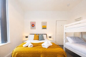 Een hotelkamer met een bed, twee bedlampen, een raam en een stapelbed.