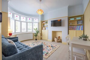 Ein gemütliches Wohnzimmer mit einer Couch, einem Fernseher, einem Kamin und einem Bücherregal.