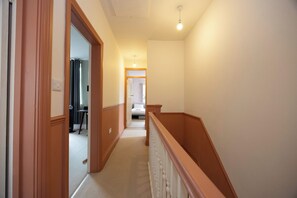 Un corridoio con ringhiera in legno, un termosifone e un letto in lontananza.