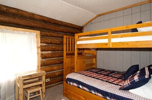 A bunk bed with a wooden headboard, a small wooden desk, and a plaid-patterned bedspread. - Peaceful Cabin with Fire Pit & Endless Trail Adventures in Island Park, Idaho (Island Park)