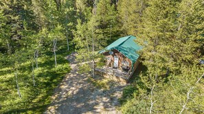 A cabin with a green roof, surrounded by dense forest. - Peaceful Cabin with Fire Pit & Endless Trail Adventures in Island Park, Idaho (Island Park)