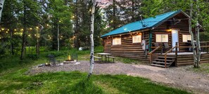 A rustic cabin with a porch, a fire pit, and string lights. - Peaceful Cabin with Fire Pit & Endless Trail Adventures in Island Park, Idaho (Island Park)