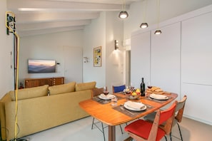 A modern living space with a dining area, sofa, and a television. - Molinella Easy Living Apartment (Modena)