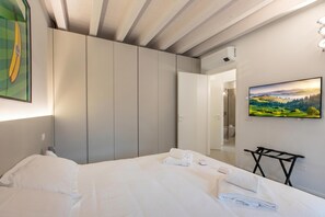 A hotel room with a bed, a wardrobe, a painting, and a television. - La Molinella Garden Suite Apartement (Formigine)