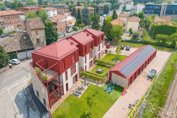A modern building with a red roof, a courtyard with seating, and a solar panel installation. - La Molinella Garden Suite Apartement (Formigine)