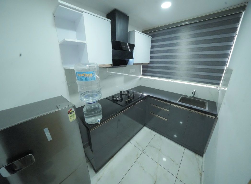 A compact kitchen with a gas stove, a water dispenser, and a window with blinds.