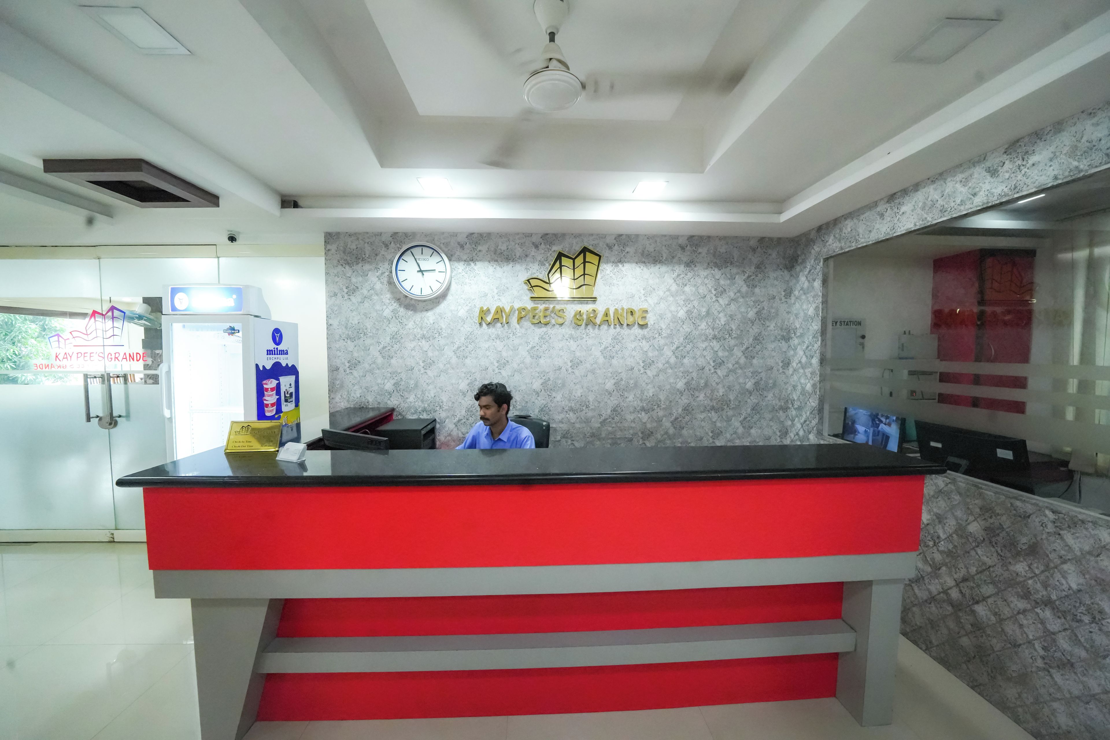 A reception desk with a clock, a wall-mounted sign, and a counter with a red and grey design.