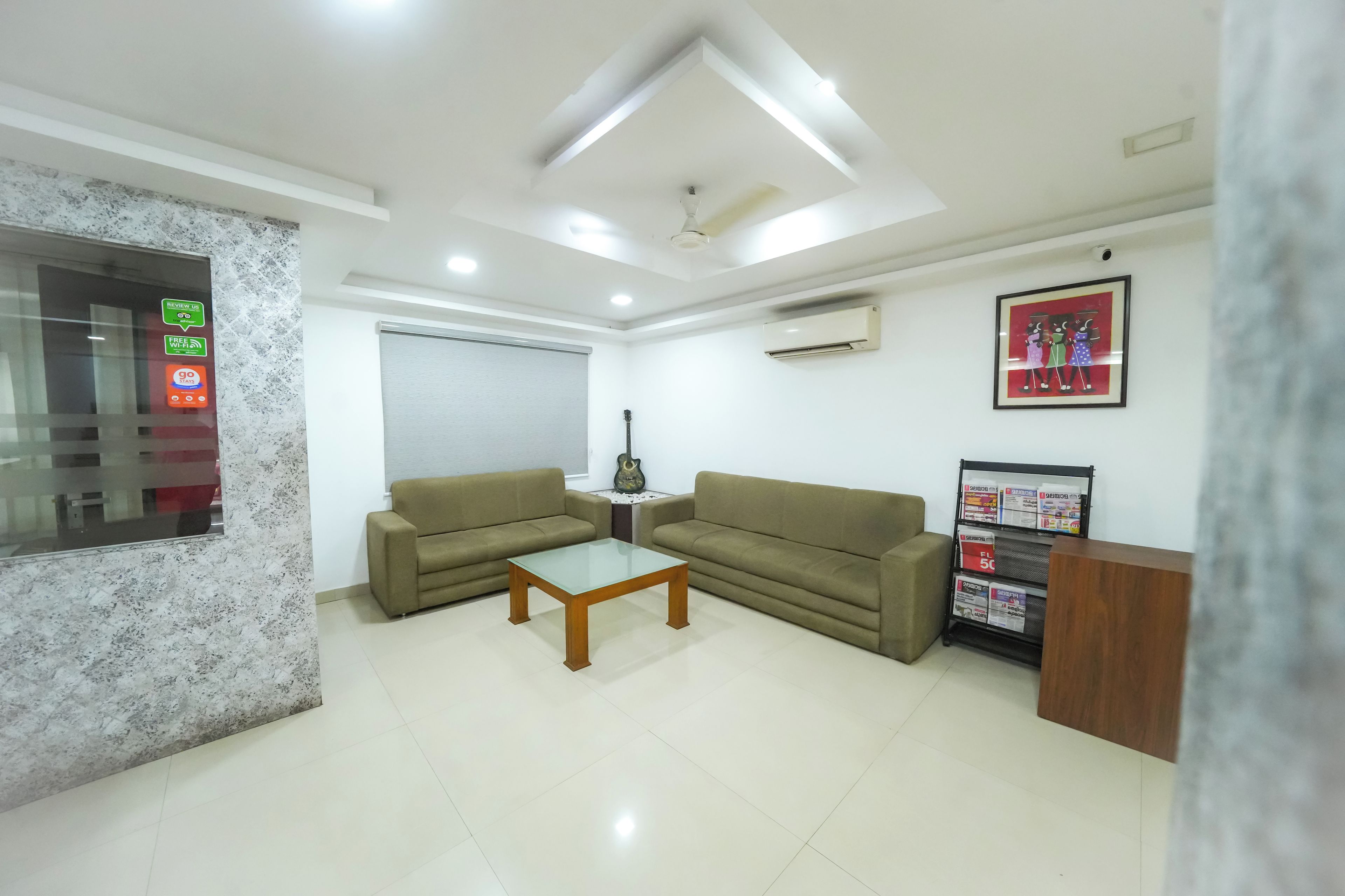A modern living room with two sofas, a coffee table, a guitar, and a wall-mounted air conditioner.