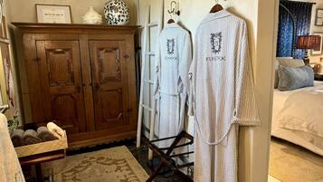 A bathroom with a wooden cabinet, a drying rack, and a bed with a blue curtain.