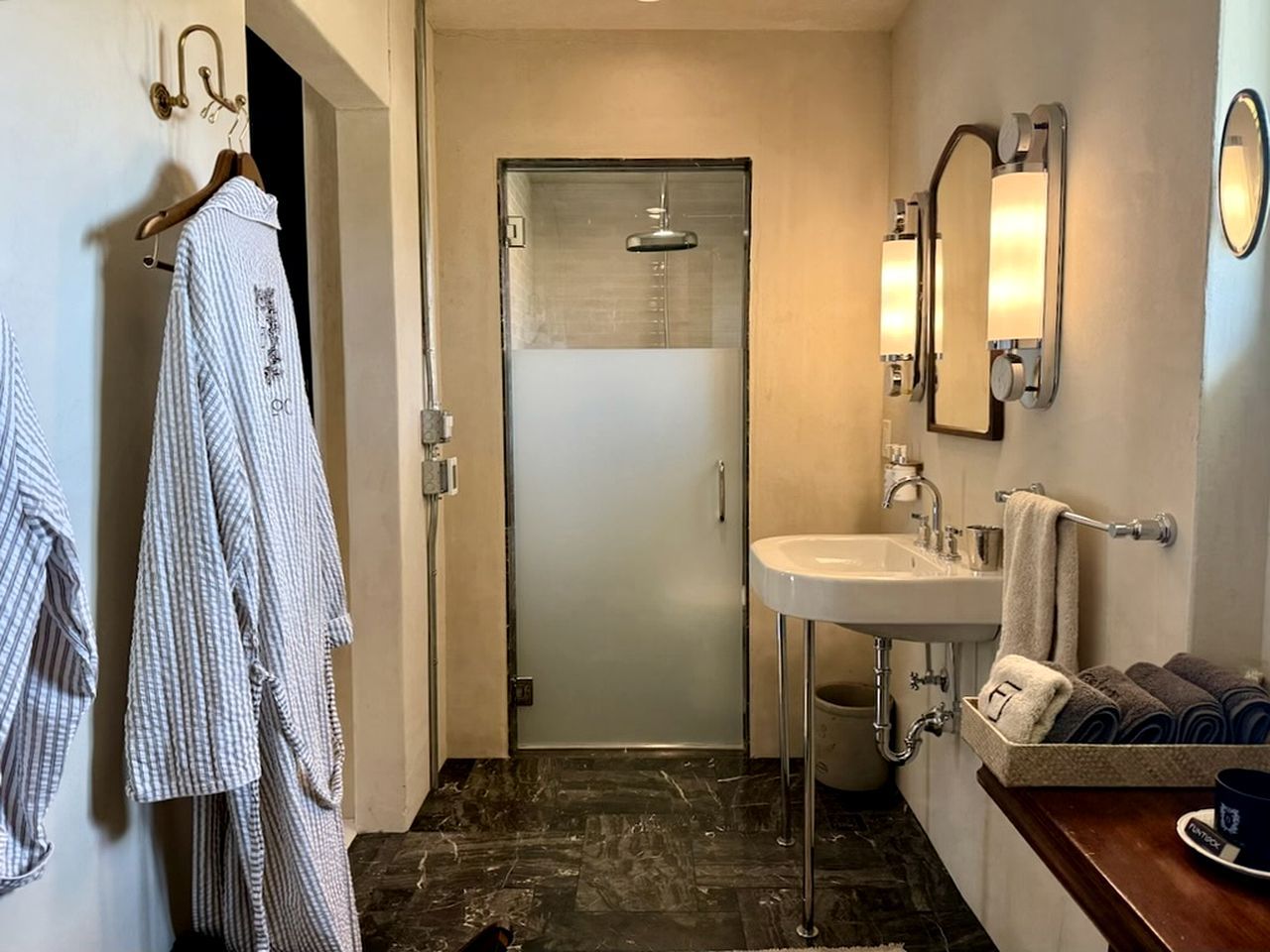 Een badkamer met douche, wastafel en handdoekrek.