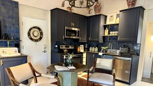 A compact kitchen with dark cabinets, a central island, and two chairs. - Serene Ranch Guesthouse with Fire Pit & Pond Views in Decatur, Texas (Decatur)