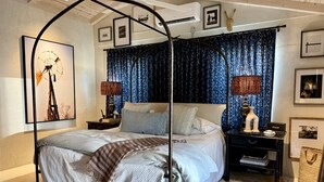A four-poster bed with a canopy, a nightstand with a lamp, and a wall-mounted air conditioning unit. - Serene Ranch Guesthouse with Fire Pit & Pond Views in Decatur, Texas (Decatur)
