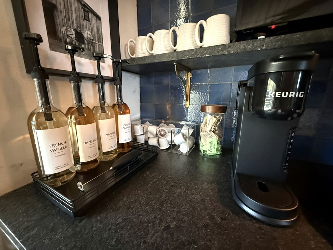 Een keukentrap met drie flessen French Vanilla, Hazelnut en Classic Caramel. Er liggen koffiekapsules en een Keurig koffiezetapparaat.