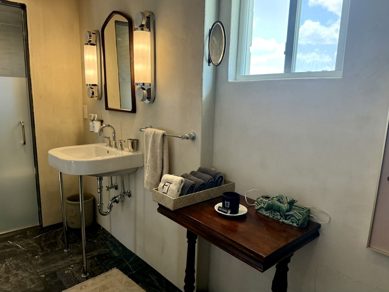 A bathroom with a sink, towel rack, and a small table with a cup and towel.