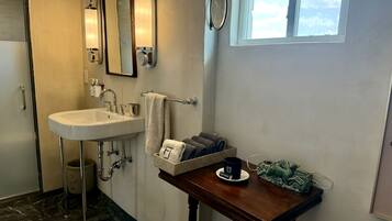 A bathroom with a sink, towel rack, and a small table with a cup and towel.