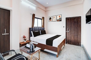 A hotel room with a bed, a desk, a chair, a TV, and a window with curtains. - Townhouse Prayag Central Junction (Prayagraj)