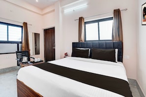 A hotel room with a bed, a desk, a chair, and a window with curtains. - Townhouse Prayag Central Junction (Prayagraj)