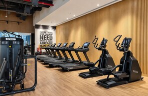 A gym with multiple treadmills and a weight machine, wooden panel walls, and motivational posters. - Luxury Studio on the Palm | Beach & Rooftop Pool (Dubai)