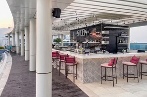A bar area with a counter, bar stools, and a view of the sea. - Luxury Studio on the Palm | Beach & Rooftop Pool (Dubai)