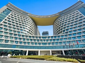 A modern building with a curved facade, large windows, and a distinctive yellow canopy. - Luxury Studio on the Palm | Beach & Rooftop Pool (Dubai)