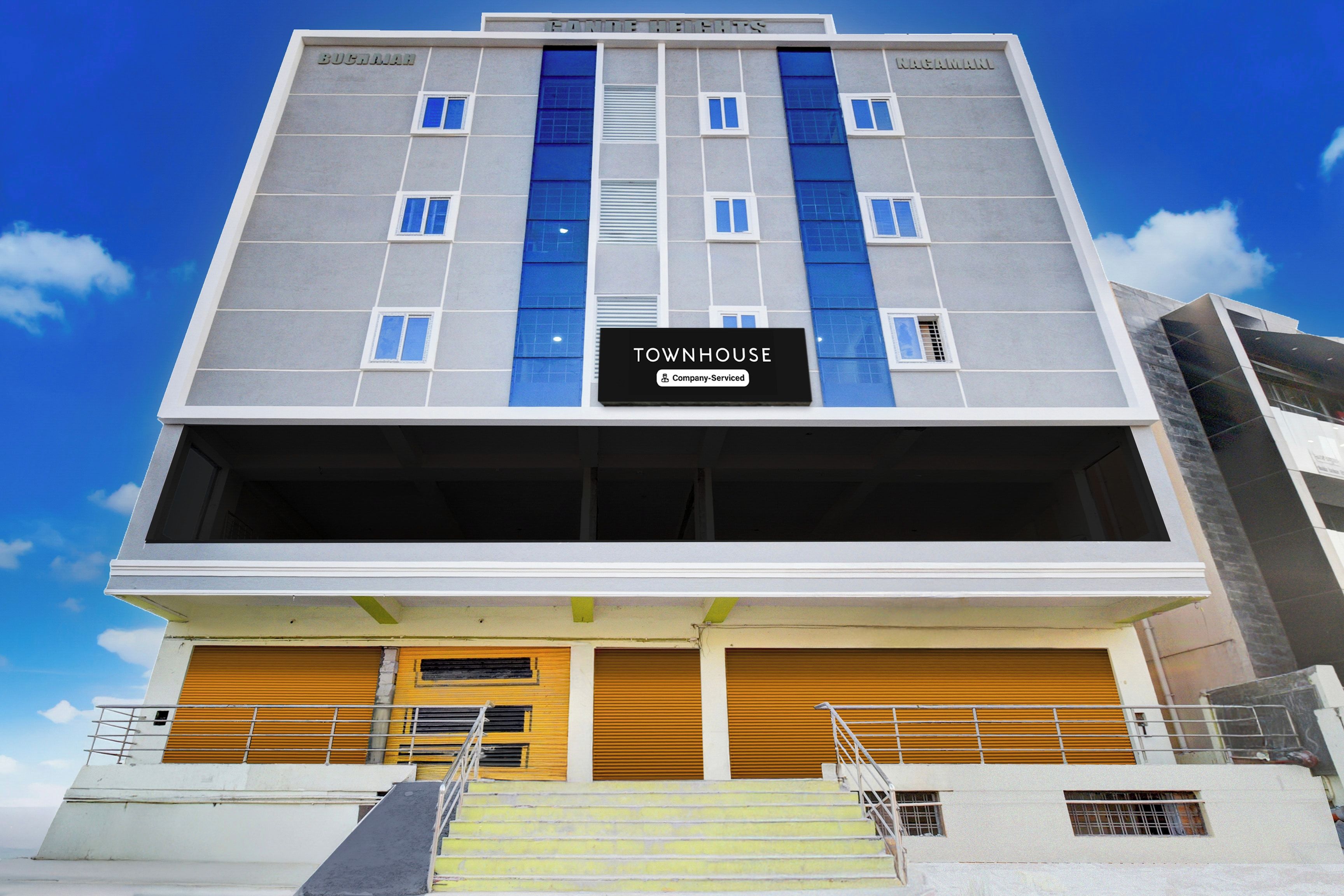 A multi-story building with a sign reading 'TOWNHOUSE' and 'Company-Serviced' indicating serviced apartments.
