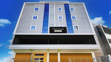 A multi-story building with a sign reading 'TOWNHOUSE' and 'Company-Serviced' indicating serviced apartments.